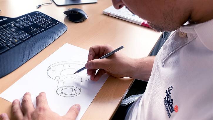 A design engineer from KEB Automation sketches the design of a brake with paper and pencil