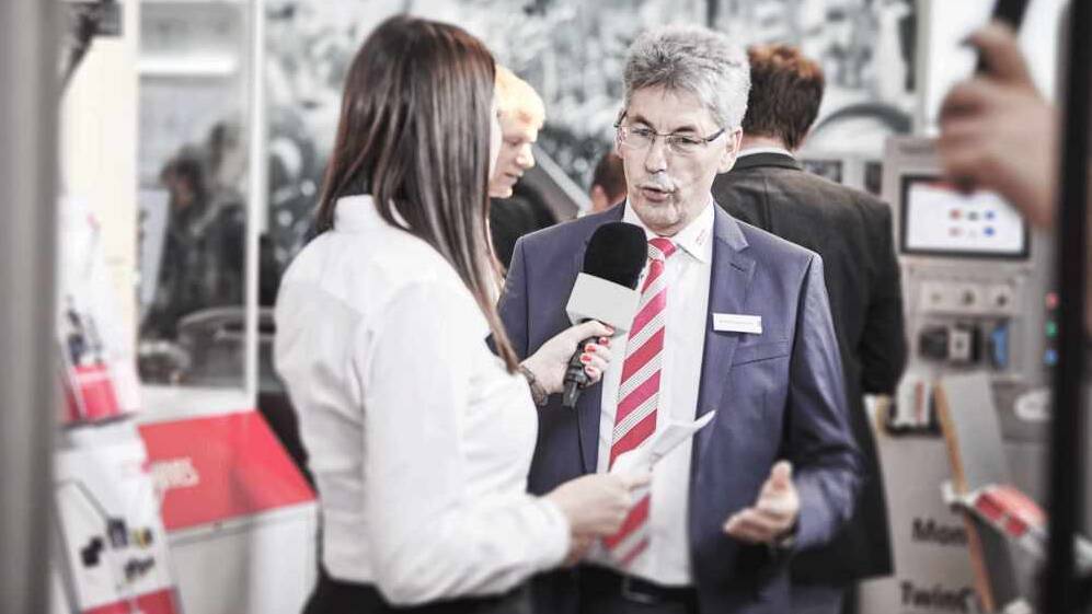 Woman interviews man at trade fair stand