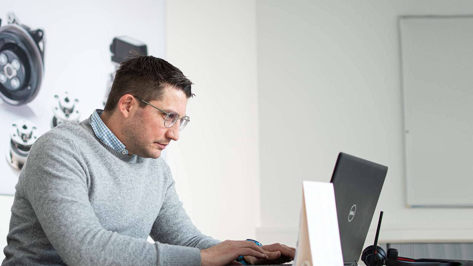 Mann sitzt am Schreibtisch und arbeitet am Notebook